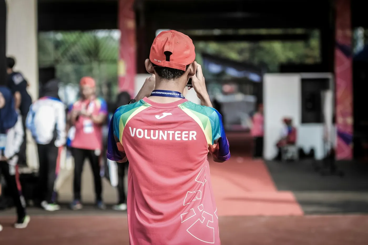 Volunteer in a bright event shirt photographing a community gathering